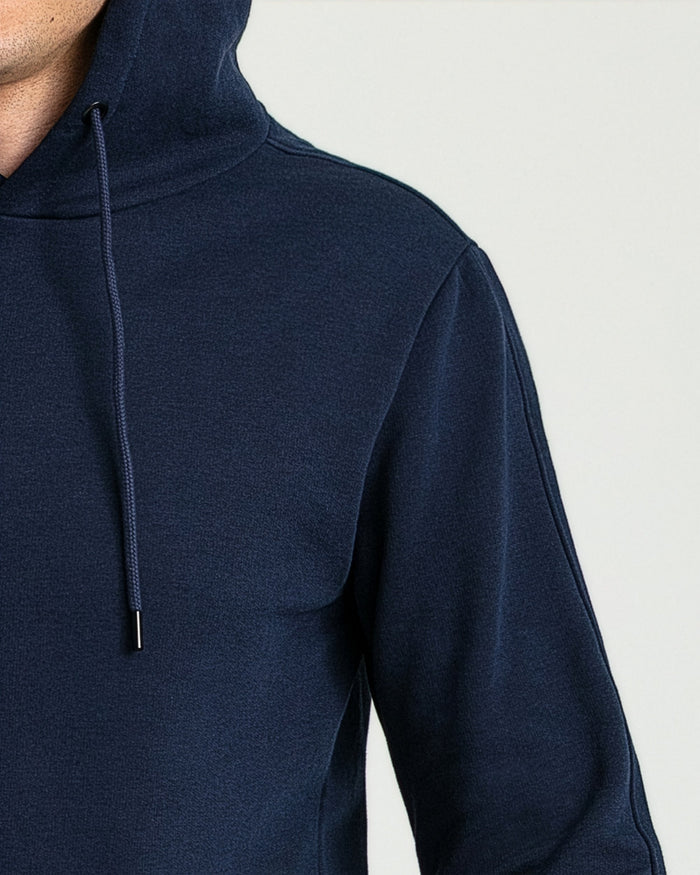 Navy pullover hoodie with drawstring and kangaroo pocket, worn by model showing front and shoulder detail.