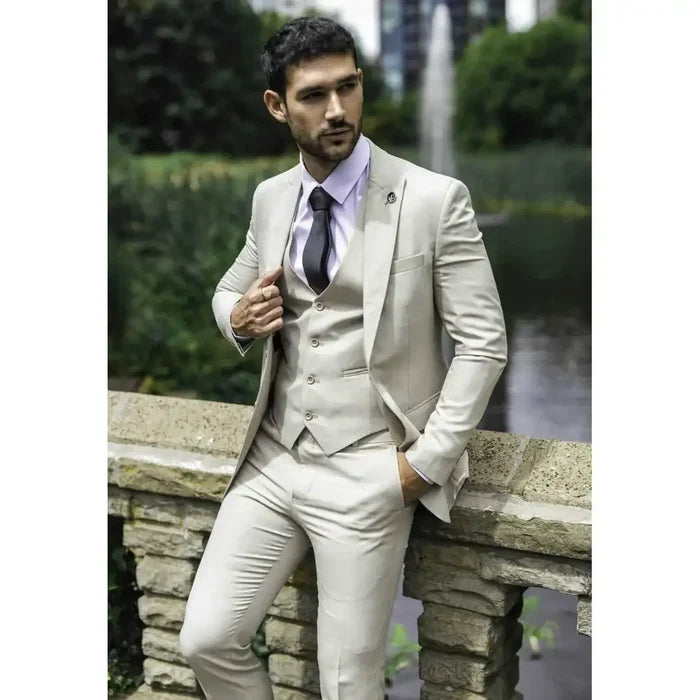 Man wearing a light beige suit with slim fit, white shirt, dark tie, standing outdoors near a water feature, stylish formal look, SKU: IM1_suit_Cream_34