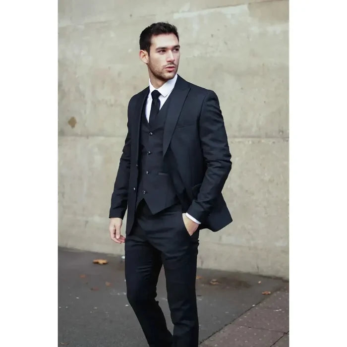 Male model wearing a classic black suit with a fitted blazer, vest, and dress pants, styled with a white shirt and black tie for business or formal events.