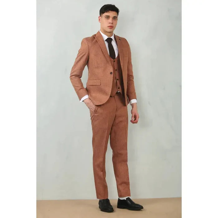 Young male model wearing a stylish camel suit with matching blazer, vest, and dress pants, paired with a white shirt and black shoes for formal events.