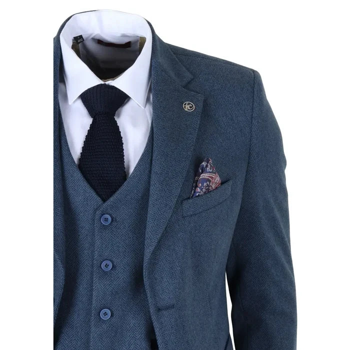 Close-up of men's blue tweed suit jacket with notch lapel, featuring a decorative lapel pin, and a patterned pocket square in the chest pocket