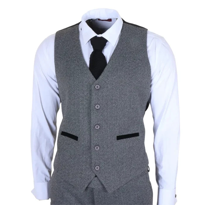 Men's grey 3 piece tweed herringbone suit with jacket, vest, and trousers, featuring a classic pattern, worn with a white shirt and black tie.