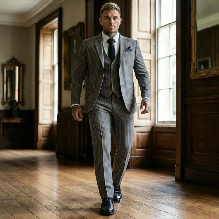 Elegant men's grey pinstripe suit with modern fit, featuring a matching blazer, vest, and trousers, styled with a white shirt, black tie, and tattoos, suitable for formal events - SKU: IM44_suit_Grey_34