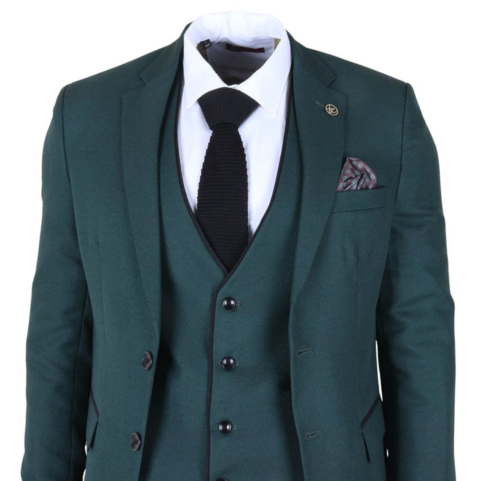 Men's tailored fit green suit jacket with notch lapel, black trim, and a gold logo pin, paired with a white dress shirt and black knit tie