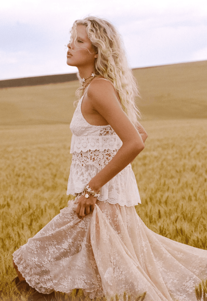 Side profile of model in cotton lace halter with underbust frill and scallop hem, styled with lace maxi skirt
