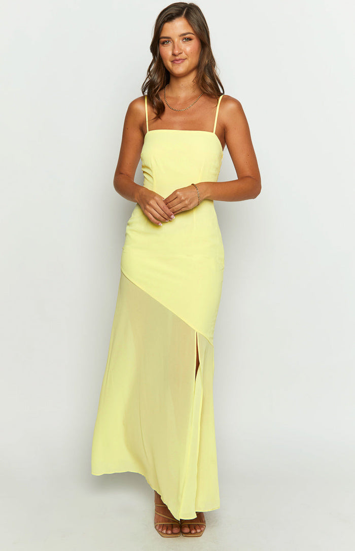 Front view of a yellow maxi dress with a square neckline, thin straps, and an asymmetrical chiffon overlay skirt with a high slit