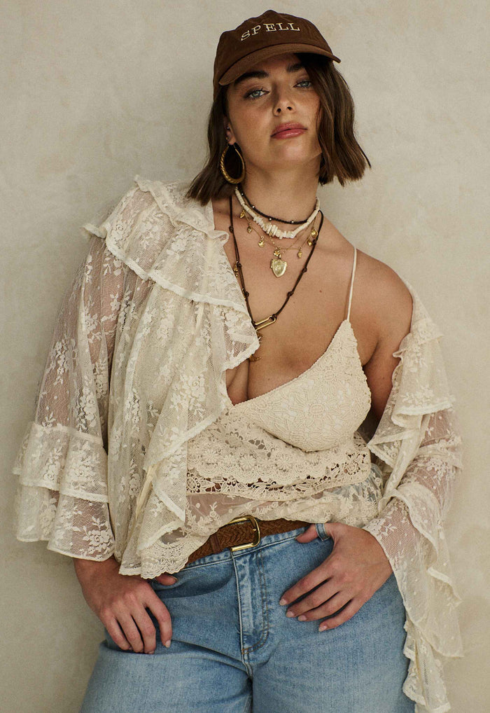 Cloud cream lace blouse laid flat showing front ties, neck ruffle, and tiered fluted sleeves