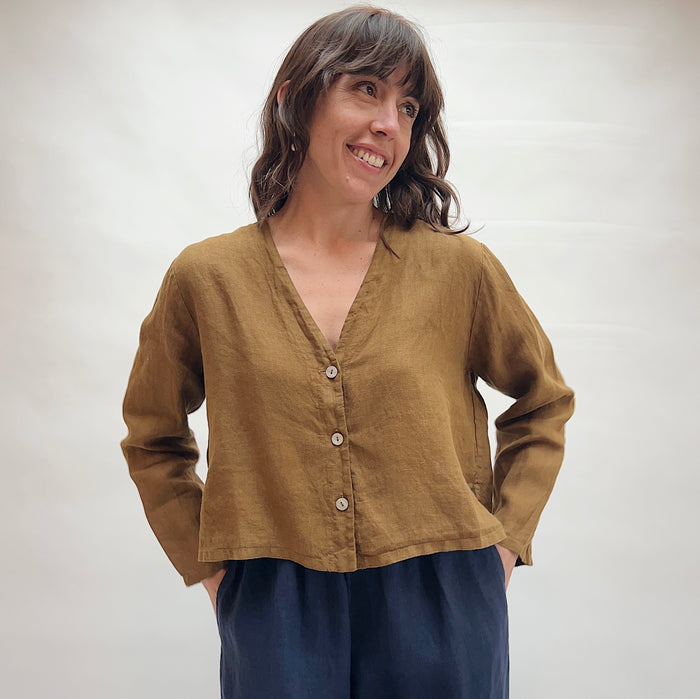Woman wearing a brown button-up shirt and blue pants against a white background