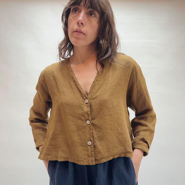 Person wearing a brown button-up shirt against a plain background
