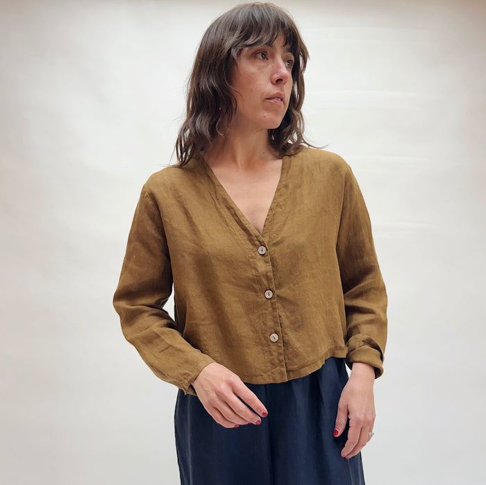 Woman wearing a brown button-up shirt against a plain background