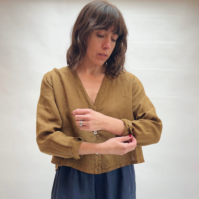 Woman wearing a brown blouse against a plain background