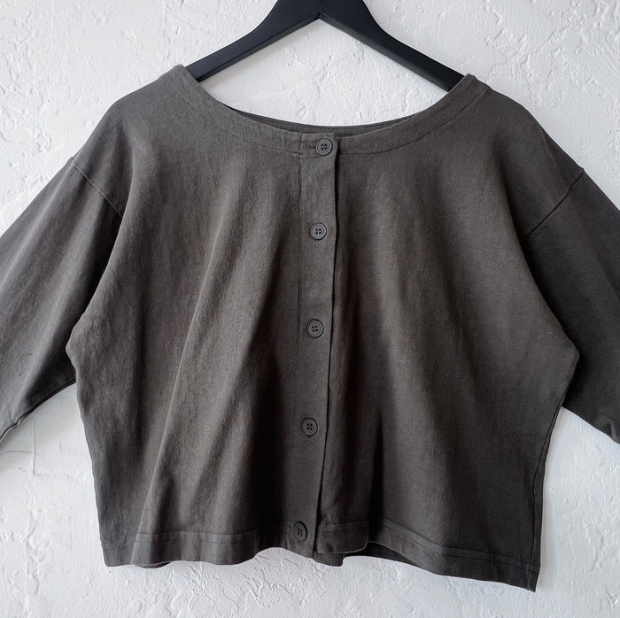 Dark grey-green button-up shirt on a hanger against a white wall