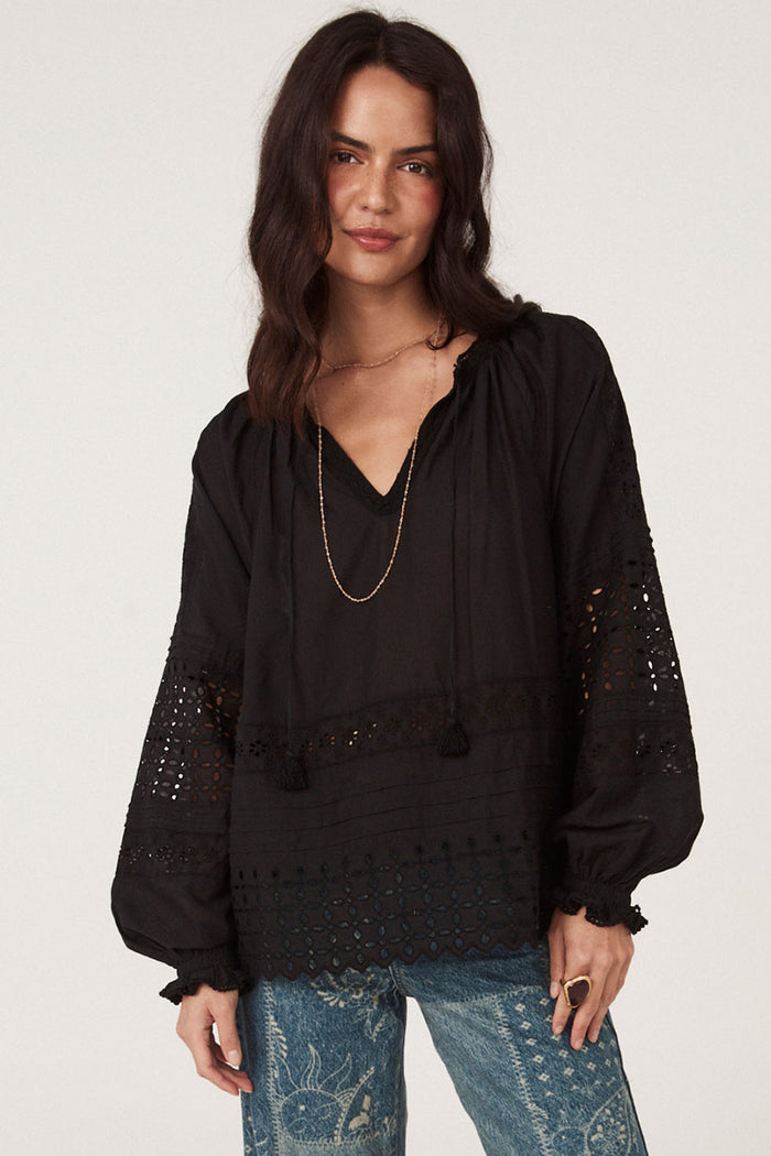 Black lace blouse front view showing anglaise detail, blouson sleeves, tassel ties, and scalloped hem on white background