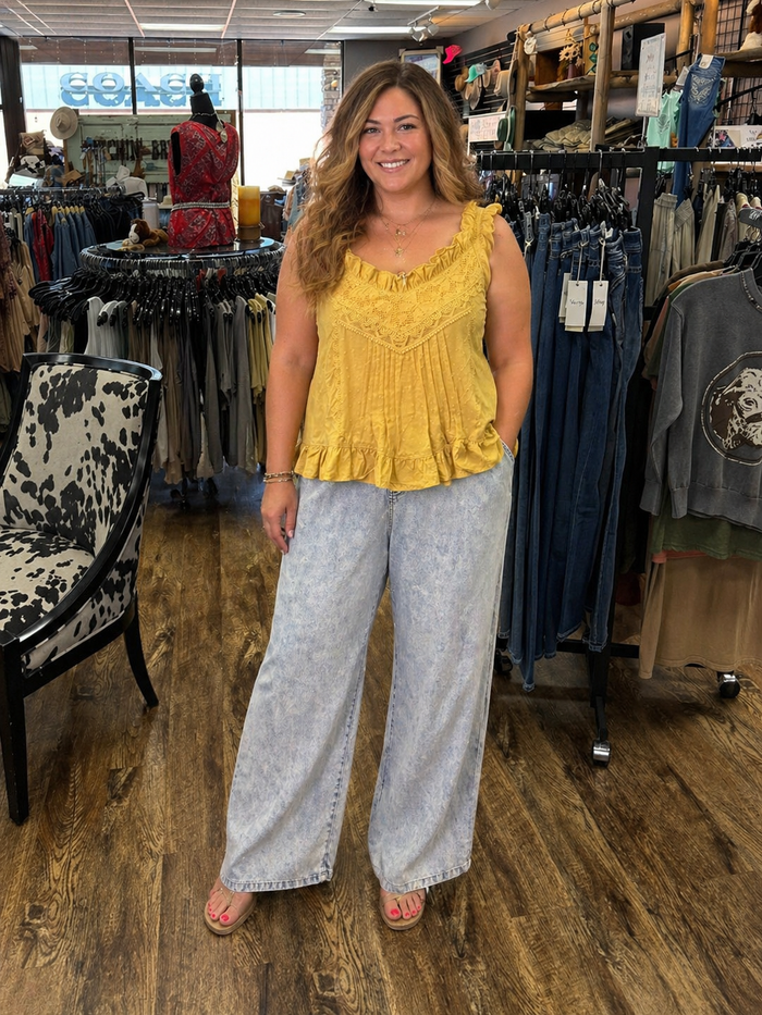 Woman wearing a yellow top and light gray pants in a clothing store.
