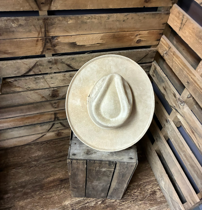 Beige cowboy hat on a wooden block against a rustic wooden background