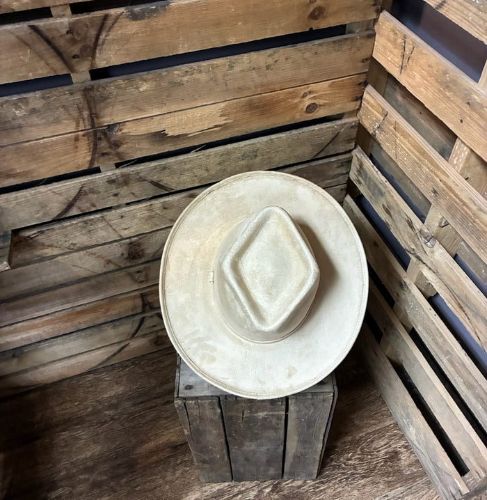 White cowboy hat on a wooden stand with wooden pallets in the background
