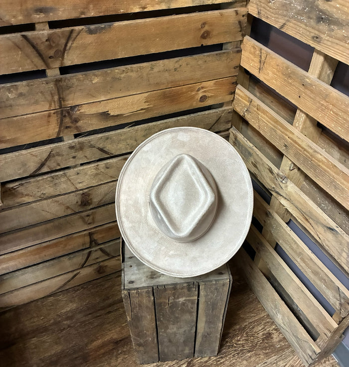 White cowboy hat on a wooden stand against a rustic wooden wall.