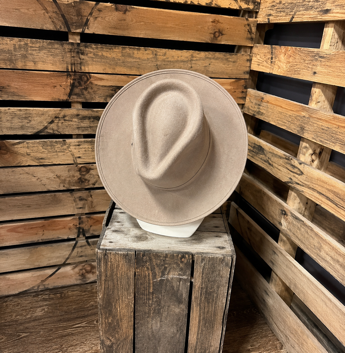 Beige hat on a wooden block against a rustic wooden background