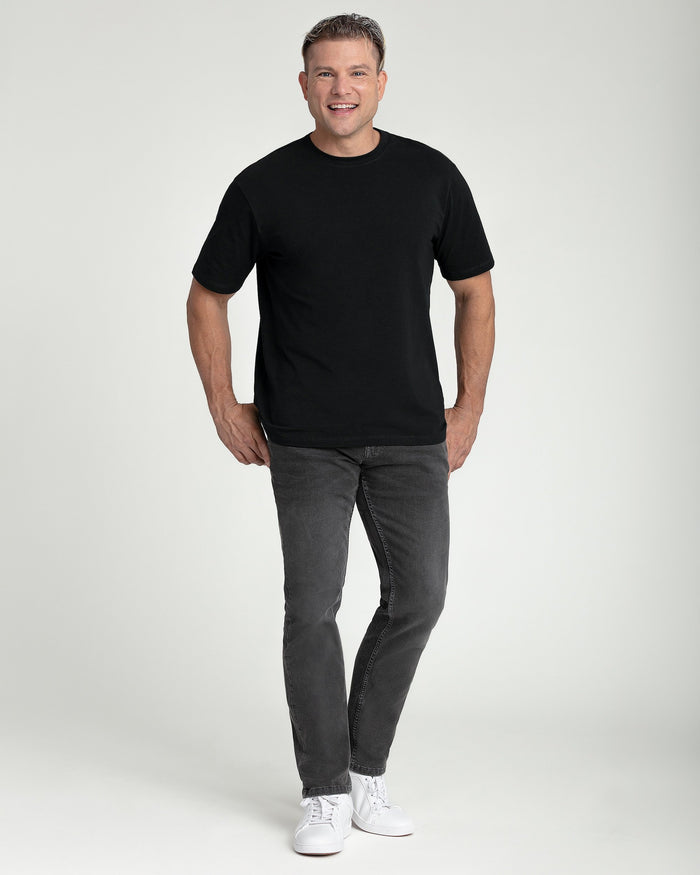 Man wearing black crew neck t-shirt with short sleeves and gray jeans.
