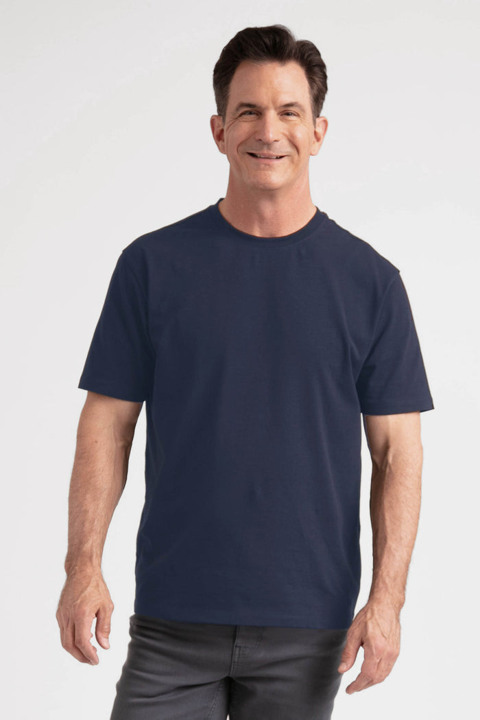 Man wearing navy crew neck t-shirt with short sleeves and gray pants.