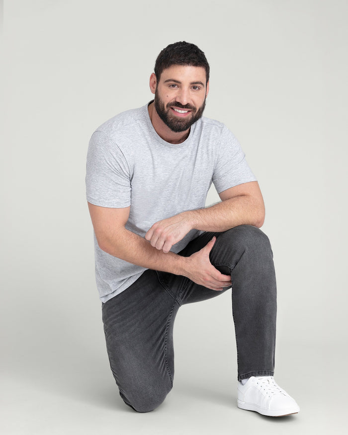 Man wearing heather grey crew neck t-shirt with short sleeves and dark jeans.