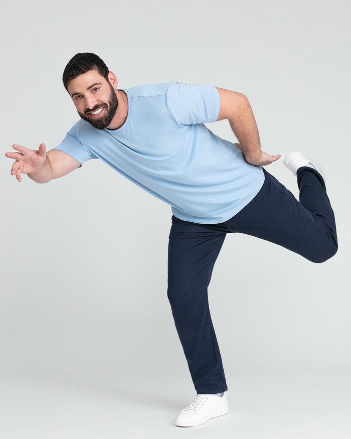 Man wearing light blue crew neck t-shirt with short sleeves and dark pants.