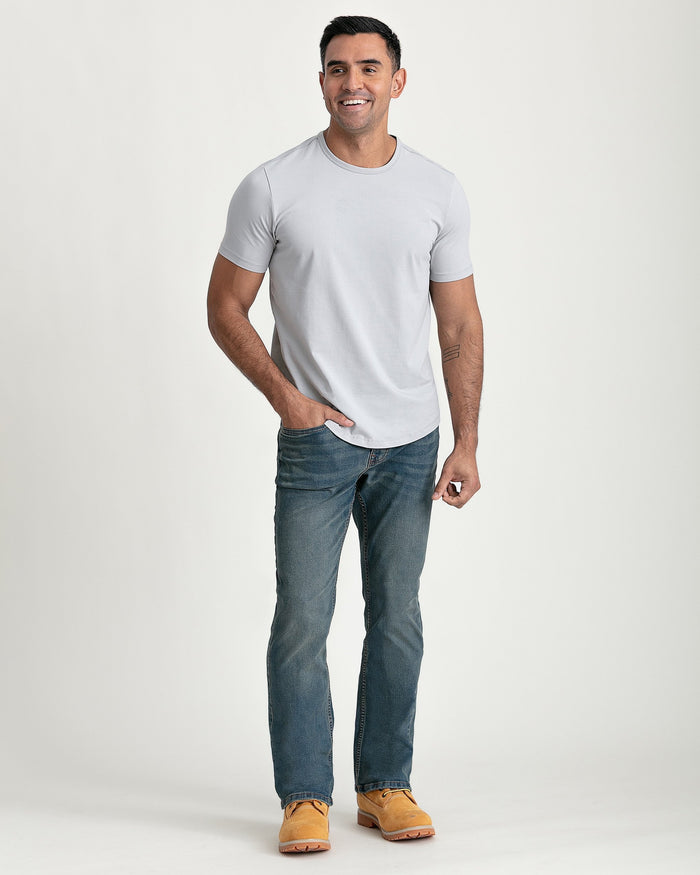 Man wearing light grey crew neck t-shirt with short sleeves and blue jeans.