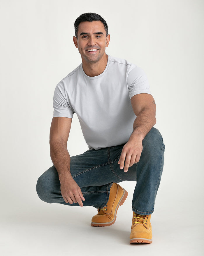 Man wearing light grey crew neck t-shirt with short sleeves, paired with dark jeans and tan work boots.