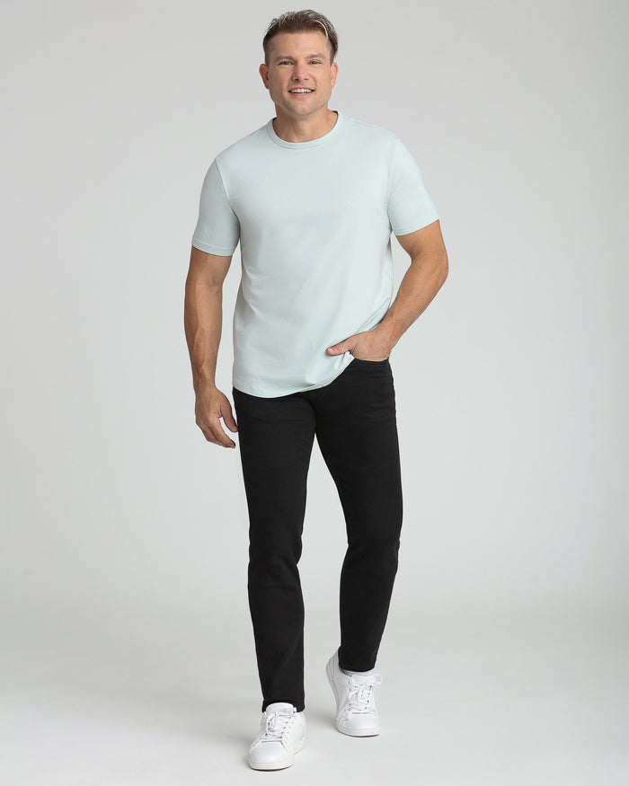 Man wearing light mint crew neck short-sleeve t-shirt with black pants and white sneakers.