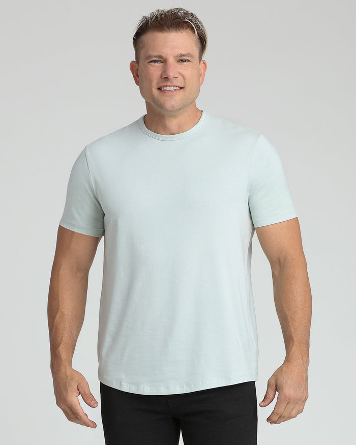 Man wearing mint crew neck t-shirt with short sleeves and black pants.