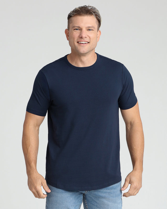 Man wearing navy crew neck short-sleeve t-shirt with light blue jeans against neutral background.