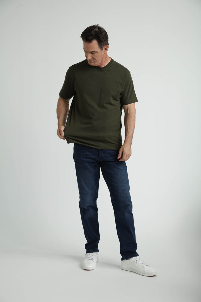 Olive crew neck t-shirt with short sleeves shown on model wearing dark blue jeans and white sneakers.
