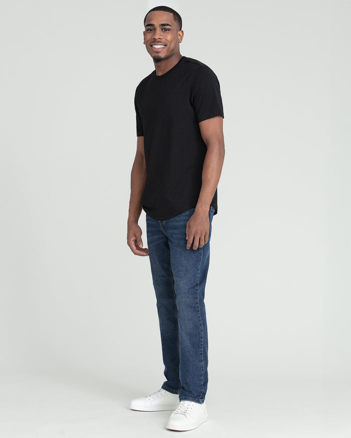 Man wearing black crew neck t-shirt with blue jeans and white sneakers.