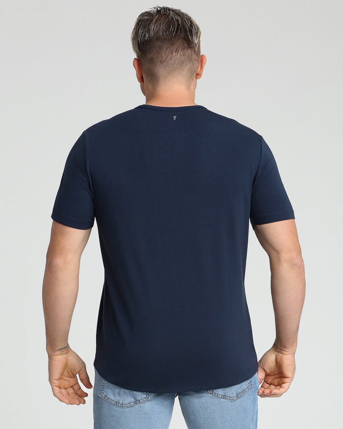 Navy crew neck t-shirt with short sleeves shown from back view on model wearing light blue jeans.