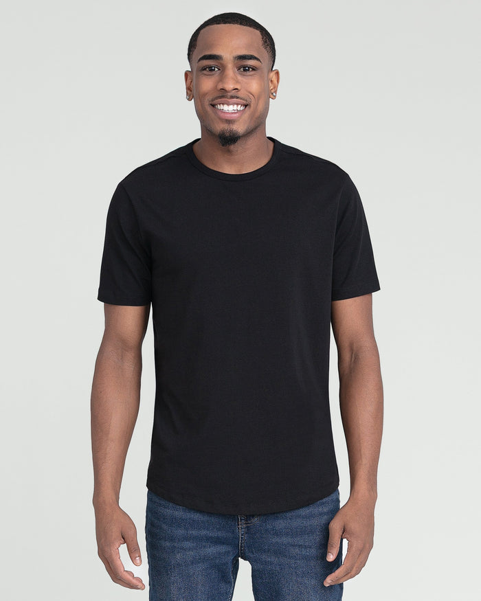 Man wearing black crew neck t-shirt with short sleeves and blue jeans against neutral background.