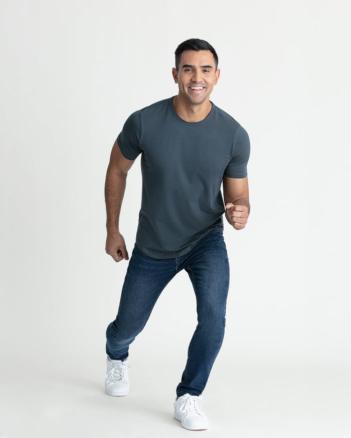 Man wearing steel gray crew neck t-shirt and dark jeans with white sneakers.