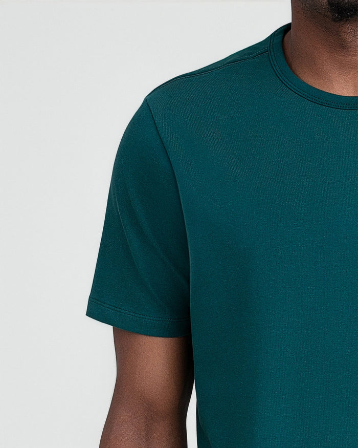 Teal crew neck t-shirt with short sleeves shown on a model against a white background.