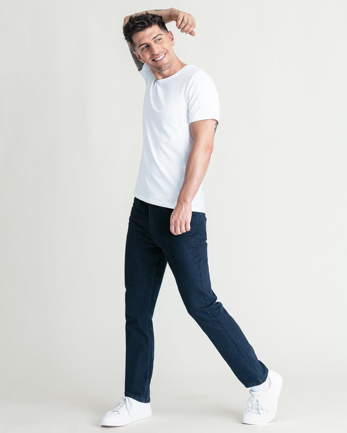 Man wearing white crew neck short-sleeve t-shirt and dark jeans with white sneakers.