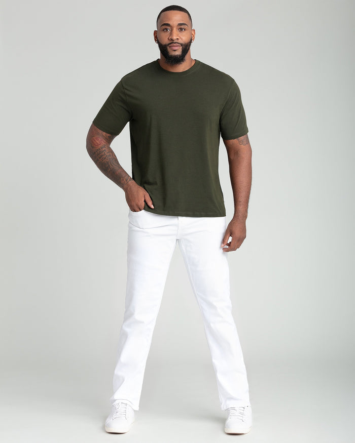 Man wearing olive crew neck t-shirt with white pants and white sneakers.