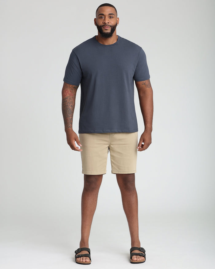 Man wearing steel gray crew neck t-shirt with khaki shorts and black sandals.