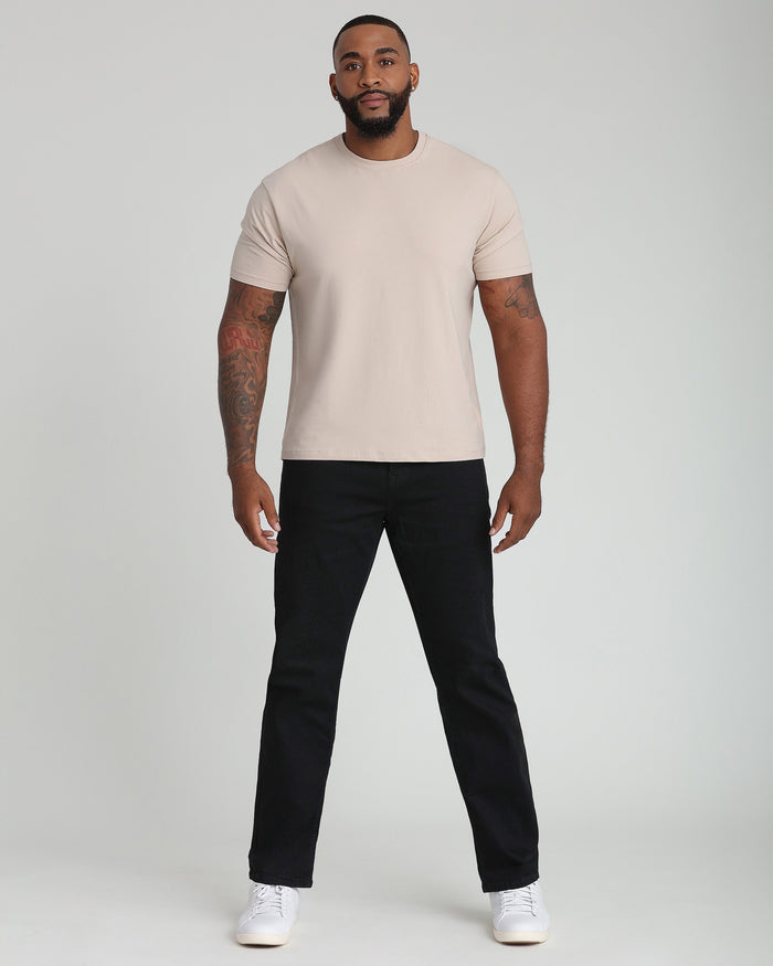 Tan crew neck t-shirt with short sleeves on male model wearing black pants and white sneakers.