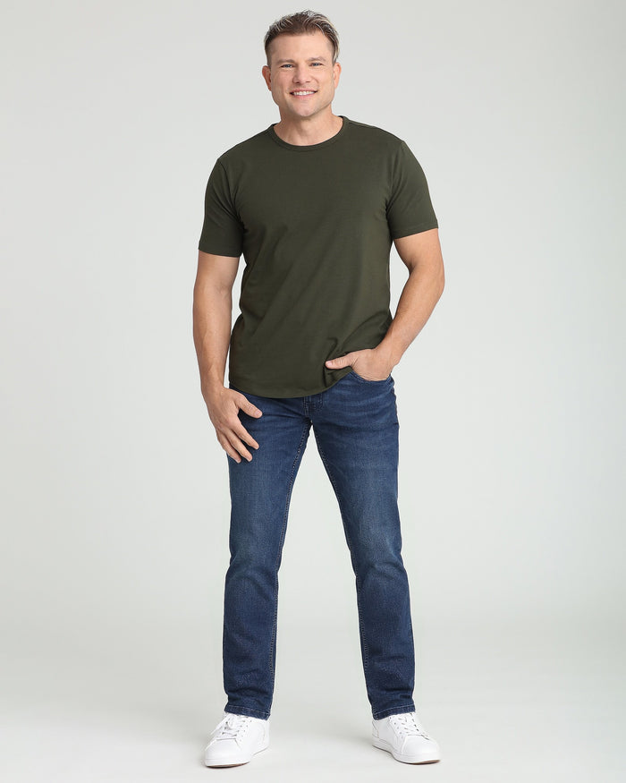 Olive crew neck t-shirt with short sleeves worn by a man paired with blue jeans.