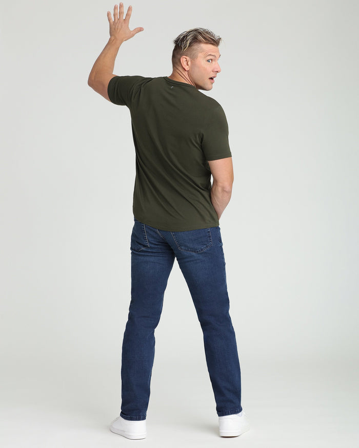 Man wearing olive crew neck t-shirt with short sleeves, shown from back view with arm raised.