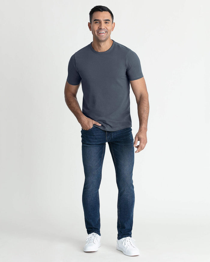 Man wearing steel-colored crew neck t-shirt with short sleeves and dark jeans.