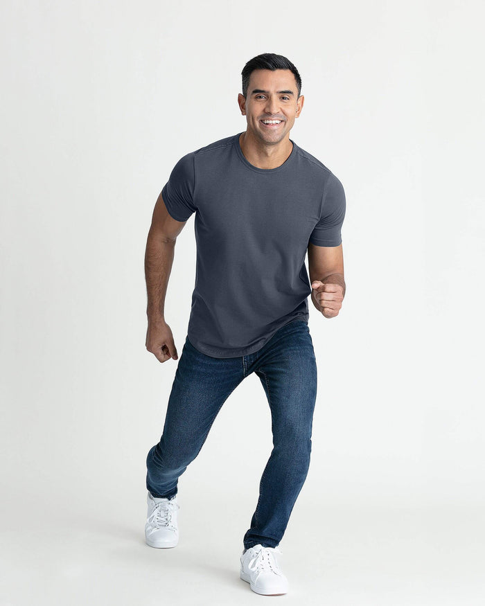 Man wearing steel gray crew neck t-shirt with short sleeves and slim fit, paired with dark jeans and white sneakers.