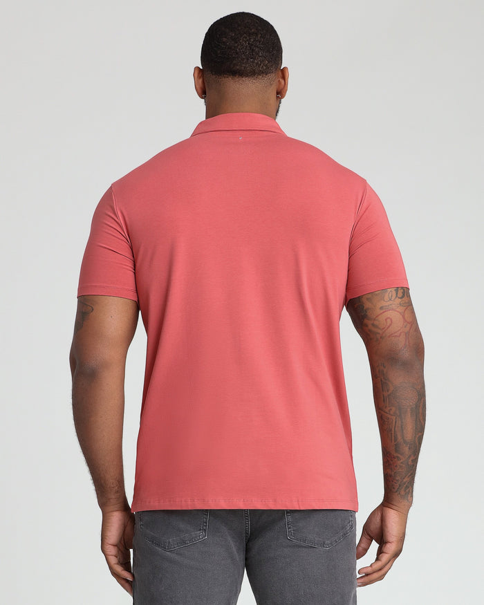 Man wearing coral pink polo shirt with collar, shown from behind, paired with gray jeans.