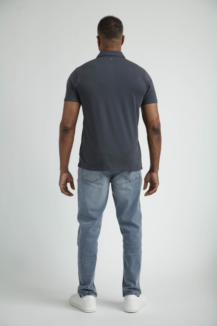 Man wearing steel grey short-sleeve polo shirt and light blue jeans, shown from back.