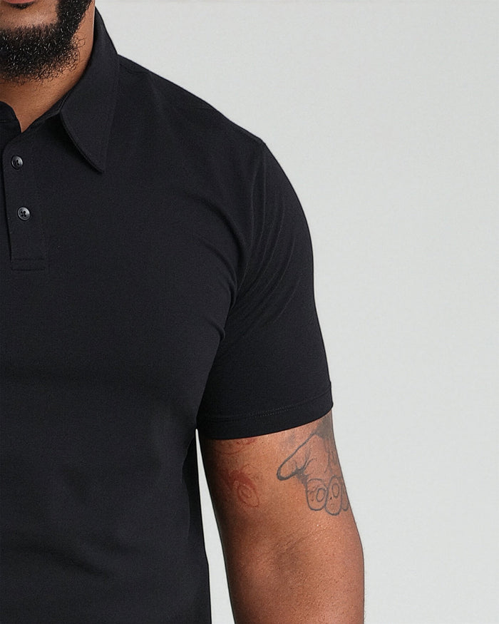 Black polo shirt with collar and button placket, shown on model.