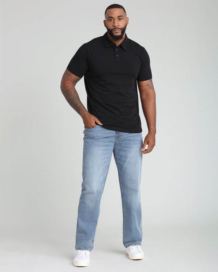 Black polo shirt with short sleeves and button placket, displayed on model wearing light blue jeans.
