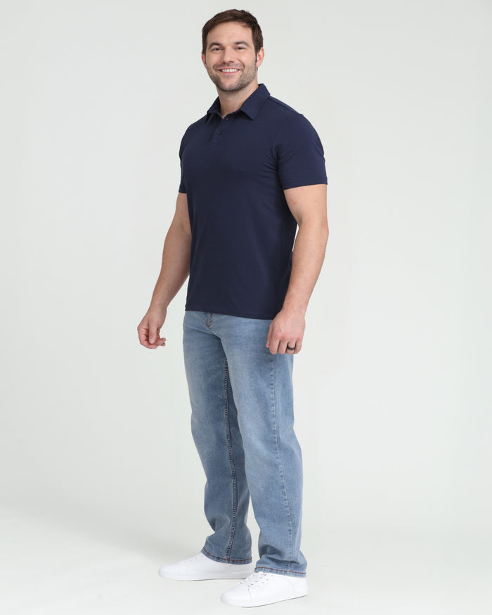 Man wearing navy short-sleeve polo shirt with collar and buttons, paired with light blue jeans and white sneakers.